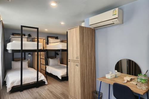 a dorm room with bunk beds and a desk and a room with a deskablish at Simply Sleep Hostel in Bangkok