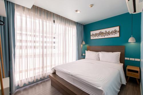 a bedroom with a large bed and a blue wall at Simply Sleep Hostel in Bangkok