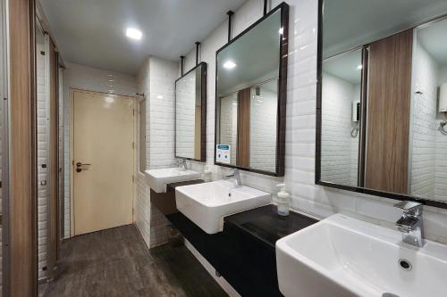 a bathroom with two sinks and two mirrors at Simply Sleep Hostel in Bangkok