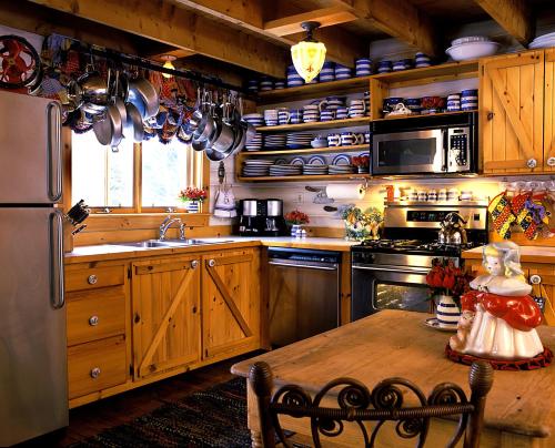 uma cozinha com armários de madeira, uma mesa e um frigorífico em Goldilocks Cabin em Stowe