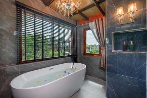 a bathroom with a tub and a window and a chandelier at The garden pool villa resort at Doi Saket in Ban Muang Wa