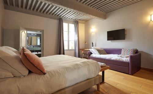 a bedroom with a bed and a purple couch at Boutique Hôtel Entraigues in Uzès