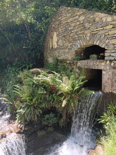 a stone bridge with a waterfall in a garden at La Petite Romance - Gîte 3 étoiles in Siran