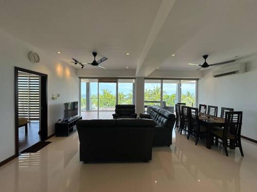 ein Wohnzimmer mit Sofas und einem Tisch und Stühlen in der Unterkunft Nilaveli Condos by Amba in Nilaveli