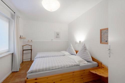 a bedroom with a bed with white sheets and a window at Ferienwohnung Familie Franke in Joldelund