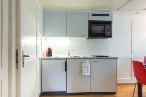 a white kitchen with a sink and a microwave at HITrental Zeughausgasse - Apartment in Zug