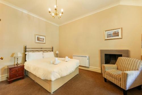 a bedroom with a bed and a chair and a fireplace at Langdale Crag in Grasmere