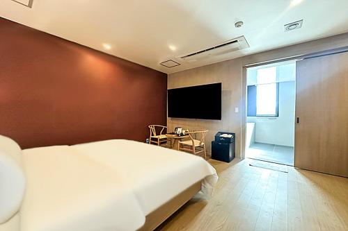 a bedroom with a bed and a tv and a table at The Hound Hotel Changwon Terminal in Changwon