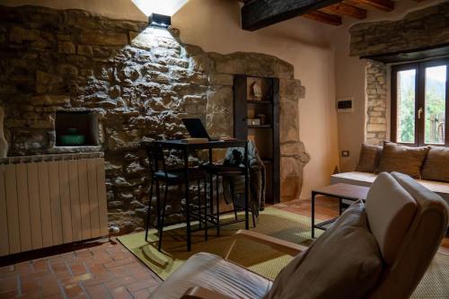 a living room with a stone wall and a table with a laptop at Serenity B&B immerso tra i monti d'Appennino in Vetto
