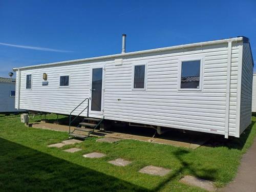 a white trailer is parked in a yard at 3 Bedroom Caravan - Sleeps 8 Parking Pets Beach in Hastings