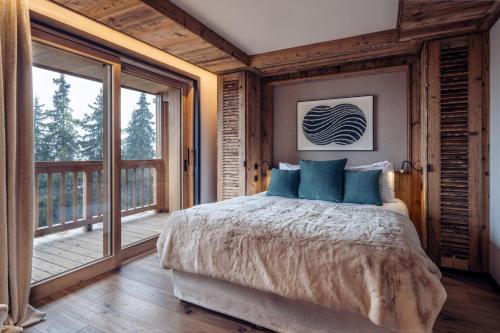 a bedroom with a large bed and a balcony at Antarès URSA 402 - luxury apartment ski inski out in Méribel