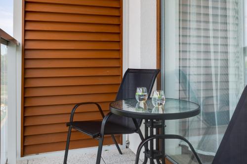 a table with two glasses of wine on a balcony at Nadmorski Apartament z Parkingiem by Rent like home in Sianozety