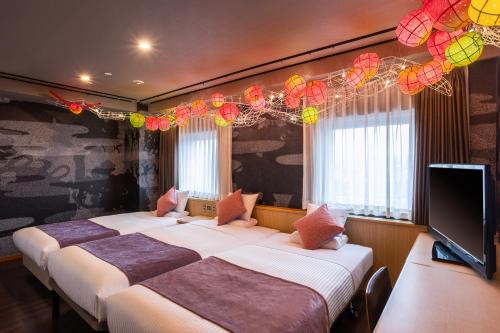 a room with three beds and a flat screen tv at ART HOTEL Aomori in Aomori