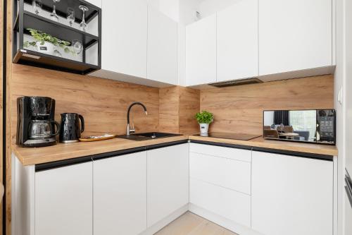 a kitchen with white cabinets and a sink at Nadmorski Apartament z Parkingiem by Rent like home in Sianozety