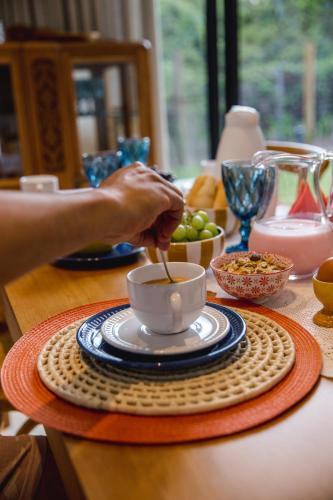 una persona sta mescolando una tazza di caffè su un tavolo di Casa Terra - Serra do Cipó a Serra do Cipo