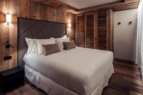 une chambre avec un grand lit blanc et des murs en bois dans l'établissement Antarès URSA 101 - luxury apartment ski inski out, à Méribel
