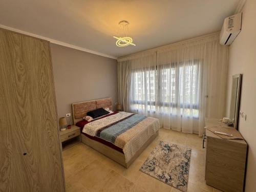a bedroom with a bed and a large window at Celia -1 Bedroom Beauty in Madīnat al Amal