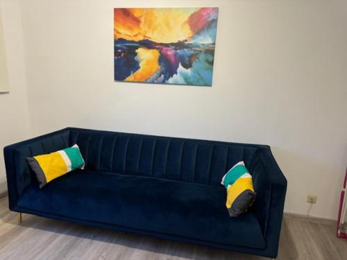 a blue couch with two pillows sitting under a painting at Rhaunen Apartments in Rhaunen