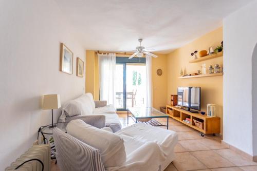 a living room with white couches and a television at Azul Zahara in Zahara de los Atunes