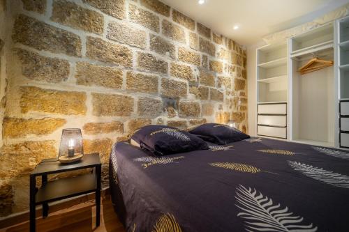 une chambre avec un lit et un mur en pierre dans l'établissement Le Nid - Spacieux, tout équipé & Climatisation, à Montpellier