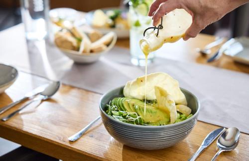 a person pouring sauce into a bowl of food at Hotel Die Krone - Immenstadt-Stein in Immenstadt im Allgäu