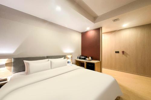 a bedroom with a large white bed in a room at The Hound Hotel Changwon Terminal in Changwon