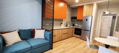 a living room with a blue couch and a kitchen at 1-Bedroom Apartment Modern, Near Downtown, with Issyk-Kul vibes in Karakol