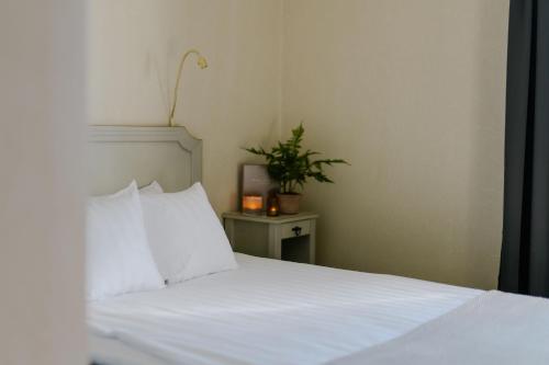 a bed with white sheets and a plant on a table at Haga Slott in Enköping