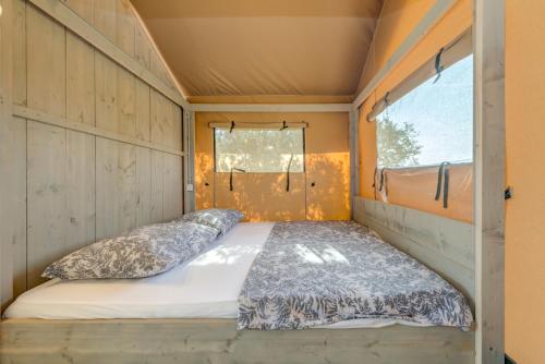 Bett in einem kleinen Zimmer mit Fenster in der Unterkunft Adriatic Heritage Glamping No2 with Jacuzzi in Donje Selo na Šolti