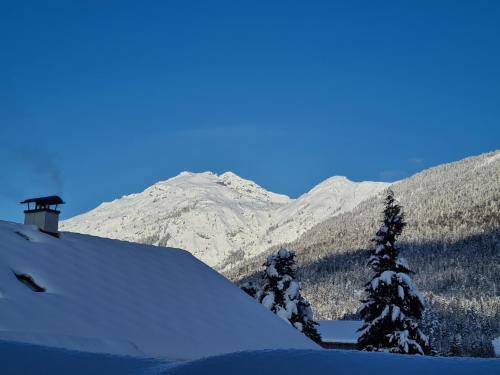 a snow covered hill with trees and mountains in the background at Haus Gaichtspitzblick in Weissenbach am Lech