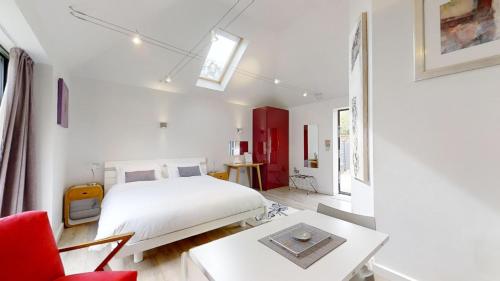 a bedroom with a white bed and a red chair at South Lodge in Milton Keynes