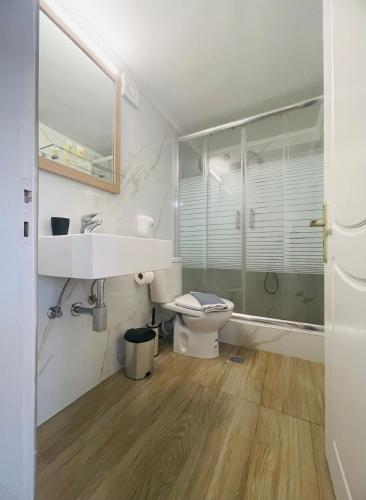 a white bathroom with a sink and a toilet at Fergani Apartments in Moúdhros