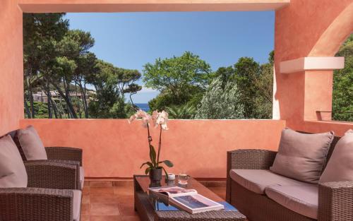a patio with chairs and a table with a view of the ocean at Hotel Cala Caterina in Villasimius