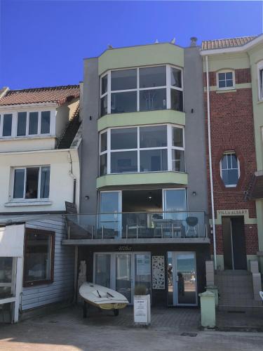 un bâtiment devant lequel se trouve une planche de surf dans l'établissement Villaloha Deluxe Bray-dunes Beach, à Bray-Dunes