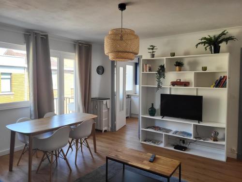 un salon avec une table et une télévision dans l'établissement Appart Cosy parking privé Croisé Laroche près tram, à Marcq-en-Barœul