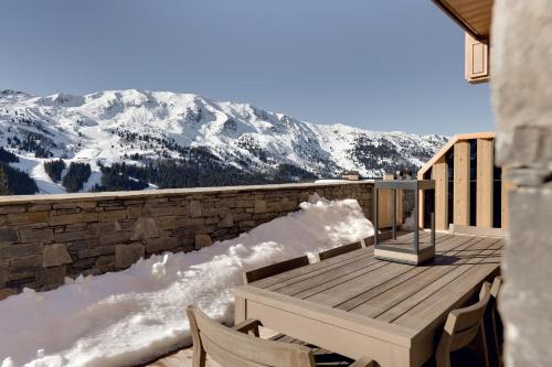 - une table et des chaises en bois sur un balcon avec des montagnes enneigées dans l'établissement Antares STELLA 002 - Ski inski out apartment, à Méribel