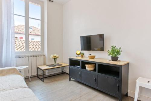 un salon avec une télévision et un canapé dans l'établissement Appartement Amarilla - Welkeys, à Biarritz