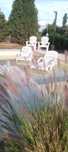 a group of white chairs sitting next to a pool at Cardozo House, casa de campo in Villa Dolores