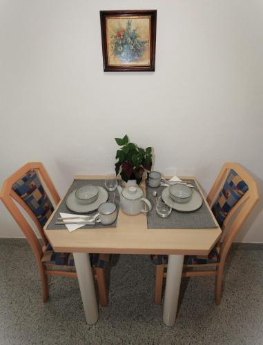 a wooden table with two chairs and a table with plates and cups at Villa Aigner in Achenkirch
