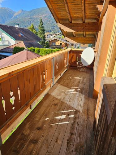 a balcony with a white chair on a wooden deck at Haus Gaichtspitzblick in Weissenbach am Lech