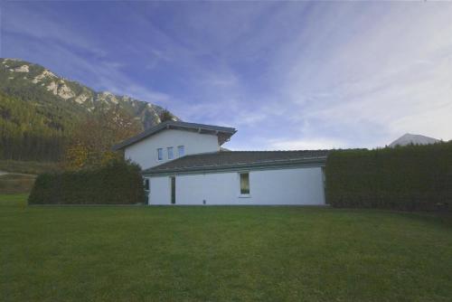 a white house in a field of grass with mountains at Villa Aigner in Achenkirch