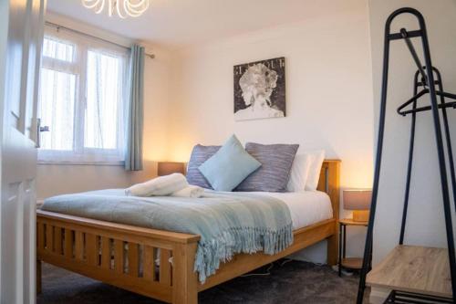 ミルトン・キーンズにある3 Bedroom home in Milton Keynes with Free Parking, WiFi and SKY TVのベッドルーム1室(木製ベッド1台、青い枕付)