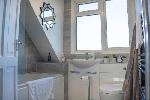ミルトン・キーンズにある3 Bedroom home in Milton Keynes with Free Parking, WiFi and SKY TVの洗面台、トイレ、窓のあるバスルーム