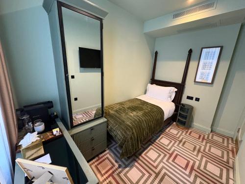 a small bedroom with a bed and a large mirror at Ellen Kensington in London