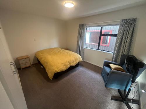 a bedroom with a bed and a chair and a window at The Iron Gate Family Hideaway - Pet Friendly in Cromwell