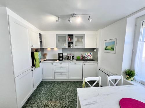 a kitchen with white cabinets and a table and chairs at COC - La Cabine in Wissant