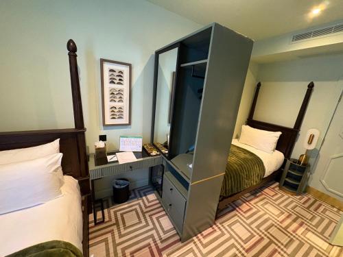 a bedroom with two beds and a desk with a mirror at Ellen Kensington in London