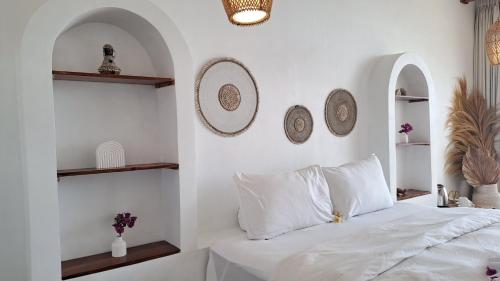 a bedroom with white walls and a bed with white pillows at The Kayuan in Kintamani