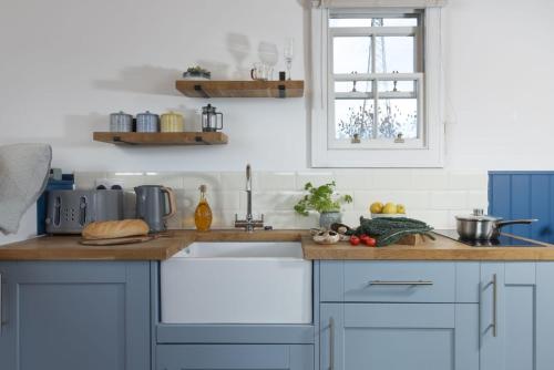 a kitchen with blue cabinets and a sink at Nori's Nest, Shepherds Hut, Croft Hooper in Ludgvan