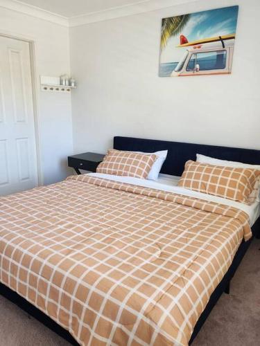 a bedroom with a bed with a orange and white plaid blanket at 2 bedroom guest suite in a Tropical setup in Baulkham Hills